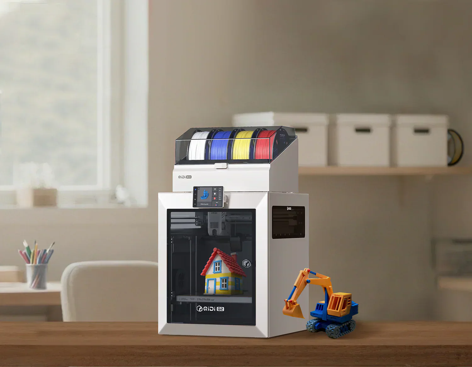 QIDI 3D printer with multi-color filament spools printing a house model, next to a toy excavator.